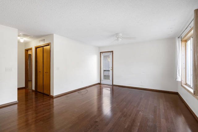 spare room featuring dark hardwood / wood-style flooring, a textured ceiling, and a wealth of natural light