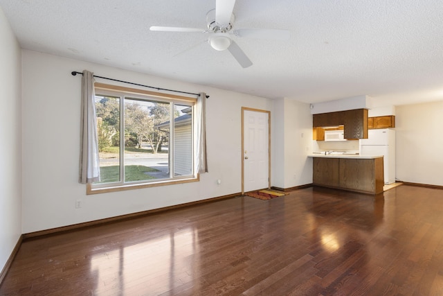 unfurnished living room with ceiling fan, dark hardwood / wood-style floors, and a textured ceiling