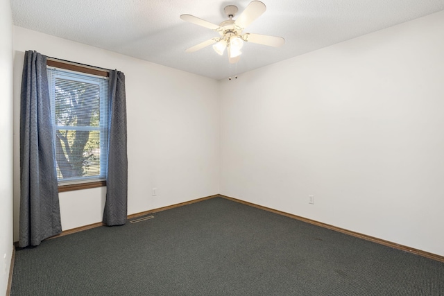 spare room with dark colored carpet, a textured ceiling, and ceiling fan