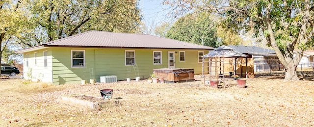 rear view of property featuring a hot tub and central AC unit