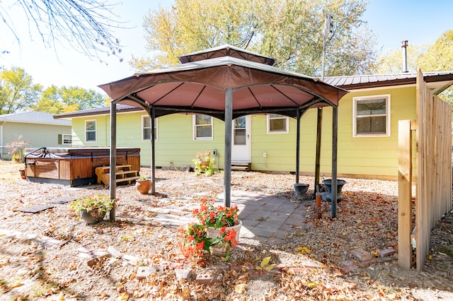 rear view of house featuring a hot tub, a gazebo, and a patio