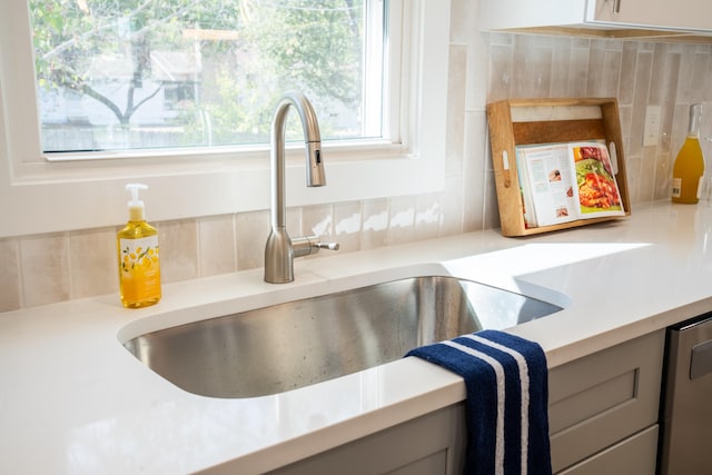 room details with gray cabinets, stainless steel dishwasher, and sink