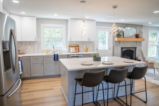 kitchen with decorative light fixtures, stainless steel appliances, light hardwood / wood-style floors, and plenty of natural light