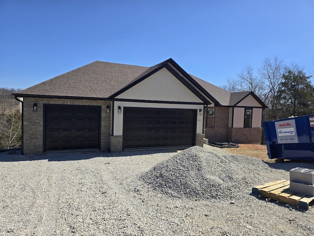 single story home featuring gravel driveway, an attached garage, and a shingled roof