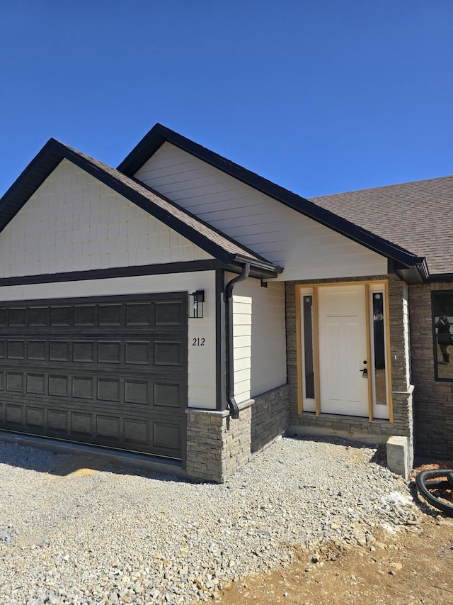 view of front of house with a garage, stone siding, and driveway