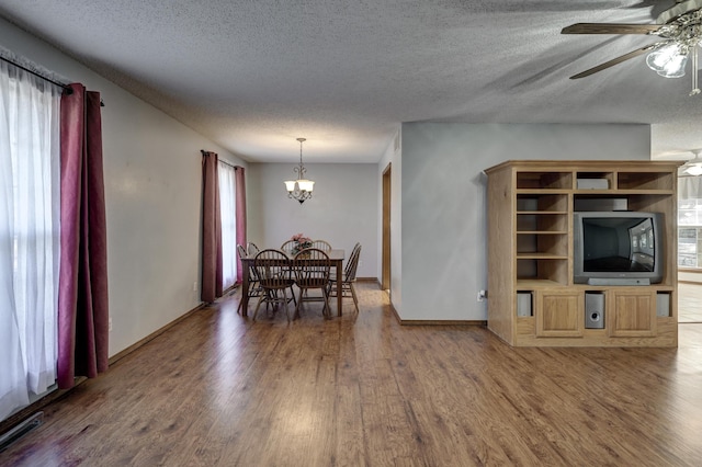 dining area featuring wood-type flooring, a textured ceiling, and ceiling fan with notable chandelier