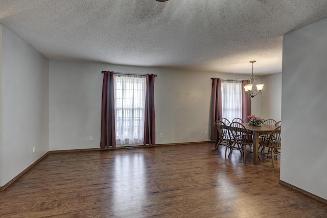 dining area with a notable chandelier, a textured ceiling, and dark hardwood / wood-style flooring