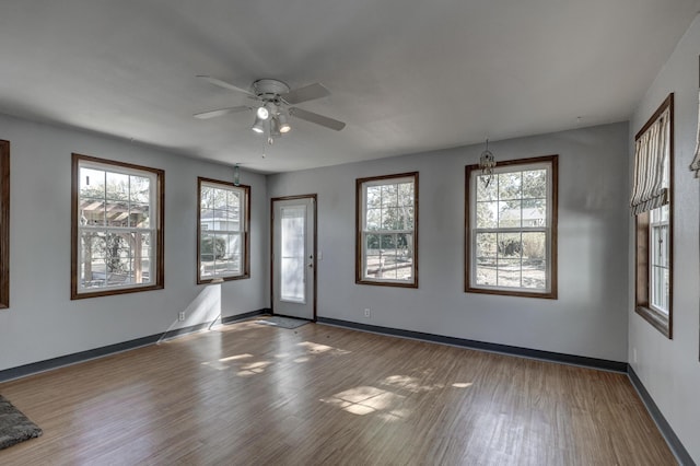 unfurnished room featuring ceiling fan, a healthy amount of sunlight, and dark hardwood / wood-style flooring