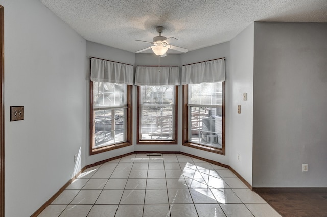 tiled spare room featuring ceiling fan, a textured ceiling, and plenty of natural light