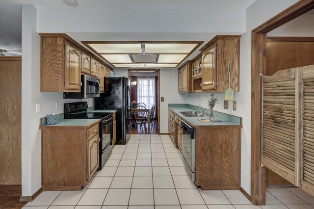 kitchen featuring sink, a textured ceiling, black appliances, and light tile patterned floors