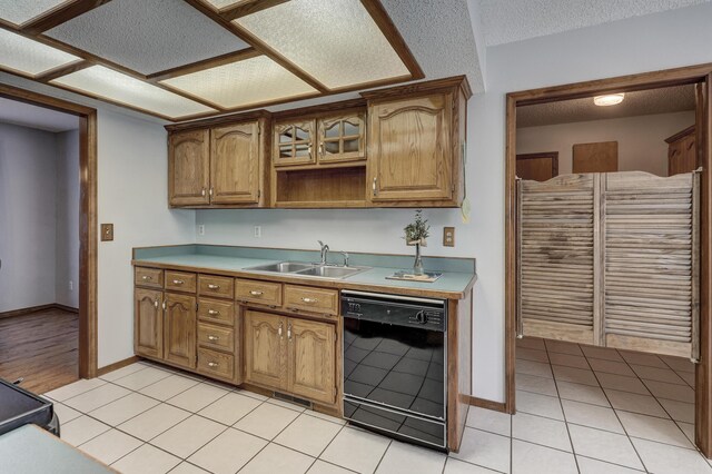 kitchen with a textured ceiling, dishwasher, sink, and light tile patterned floors