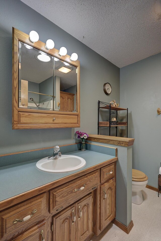 bathroom with vanity, toilet, and a textured ceiling