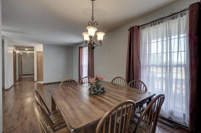 dining space with an inviting chandelier, a textured ceiling, and wood-type flooring