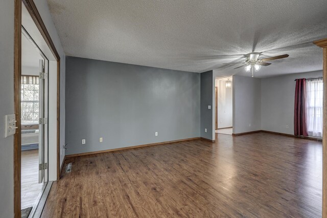 spare room with a textured ceiling, a wealth of natural light, and dark hardwood / wood-style floors