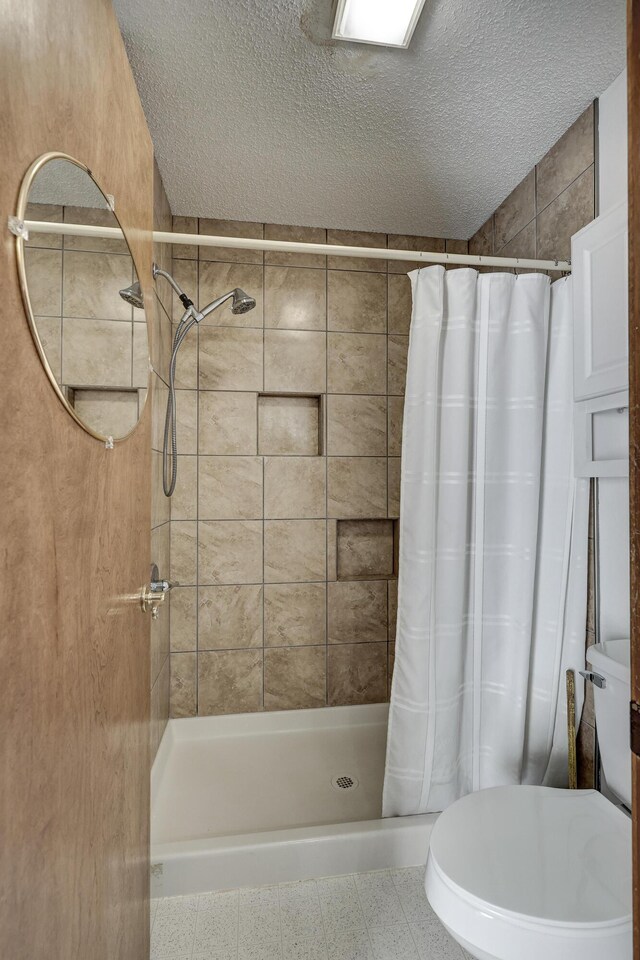 bathroom with toilet, walk in shower, a textured ceiling, and tile patterned flooring