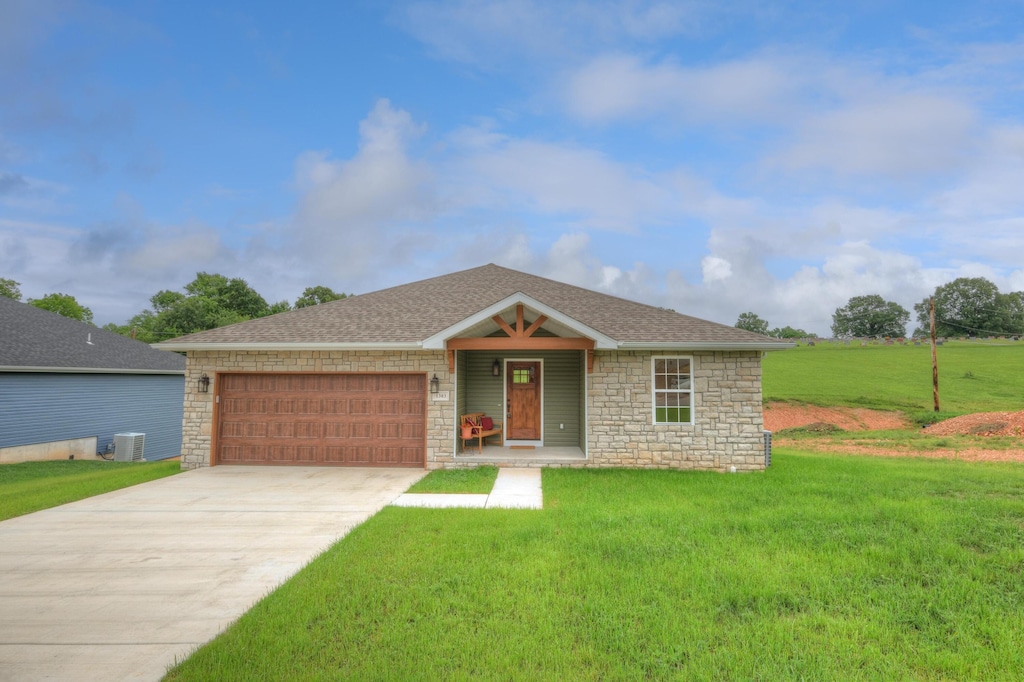 ranch-style home with a front yard, central AC unit, and a garage