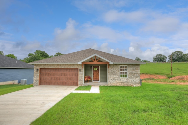 ranch-style home with a front yard, central AC unit, and a garage