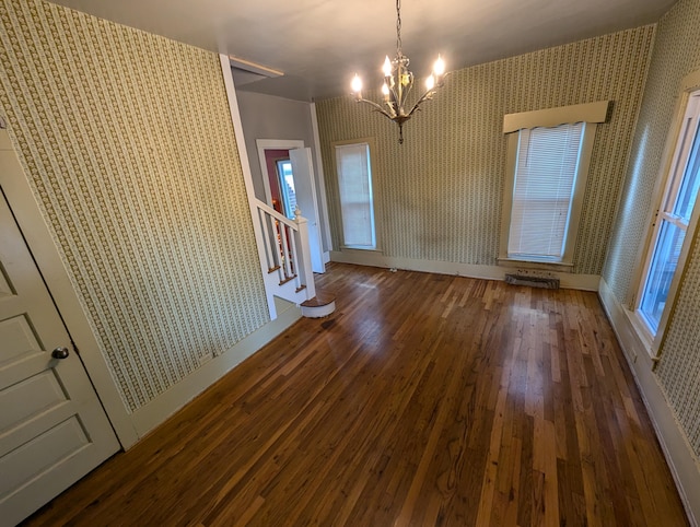 unfurnished dining area featuring an inviting chandelier and dark hardwood / wood-style flooring