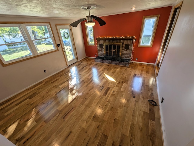 unfurnished living room featuring a textured ceiling, a brick fireplace, wood-type flooring, and ceiling fan