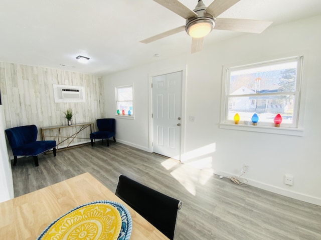 living area featuring ceiling fan, a wall mounted air conditioner, wooden walls, and wood-type flooring