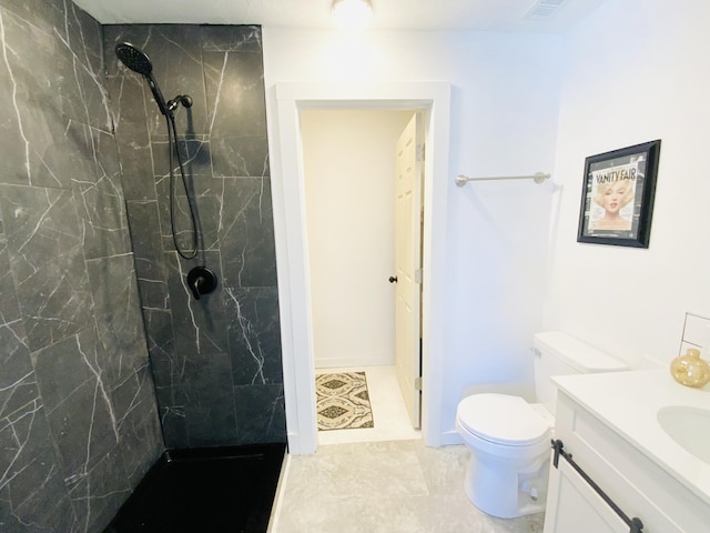 bathroom featuring vanity, toilet, and a tile shower