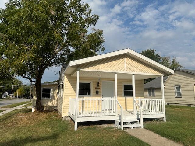 bungalow featuring covered porch and a front lawn