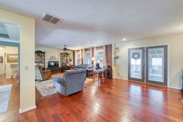 living room featuring a textured ceiling, wood-type flooring, and ceiling fan