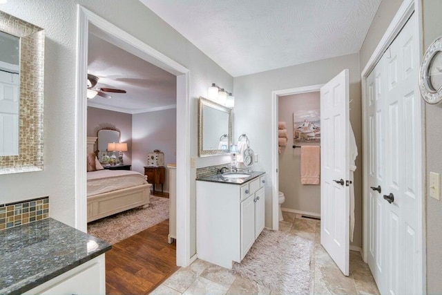 bathroom featuring hardwood / wood-style flooring, toilet, ornamental molding, vanity, and ceiling fan