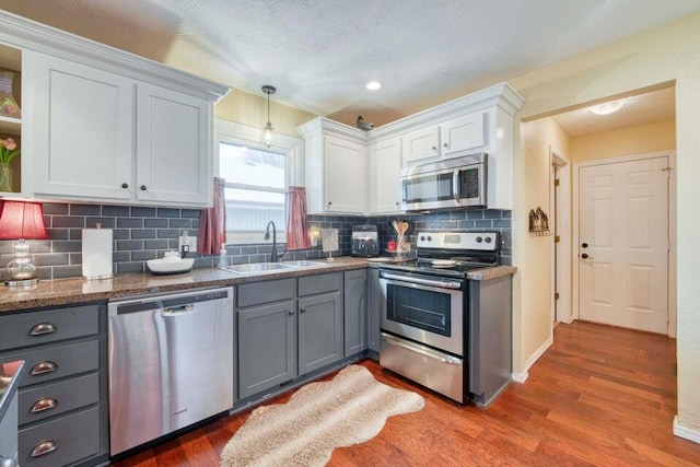 kitchen featuring gray cabinets, white cabinetry, stainless steel appliances, and sink