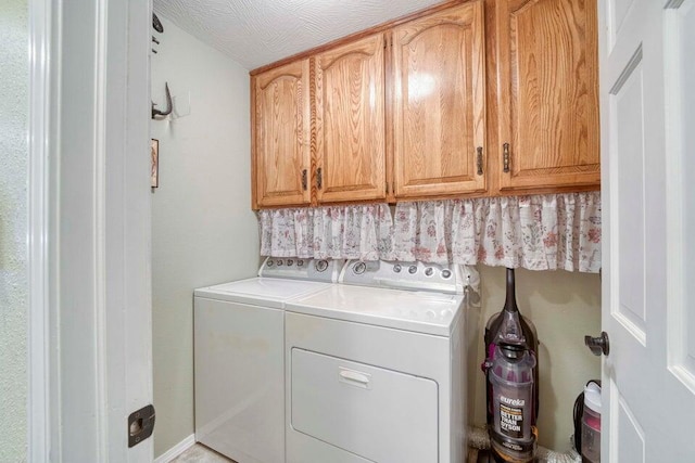 washroom featuring washer and clothes dryer, a textured ceiling, and cabinets