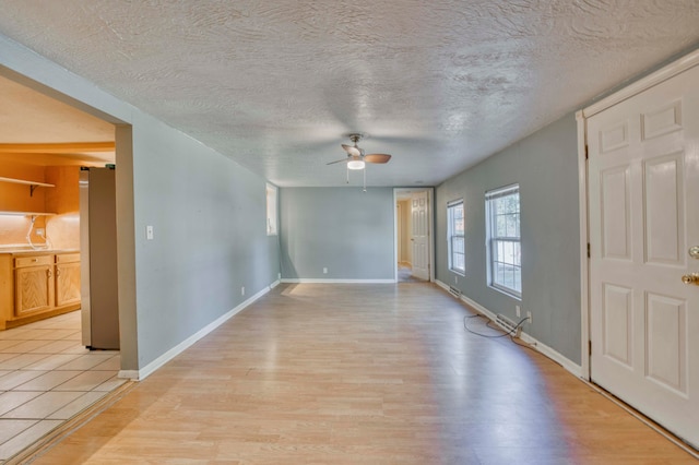 spare room featuring a textured ceiling, light wood-type flooring, and ceiling fan