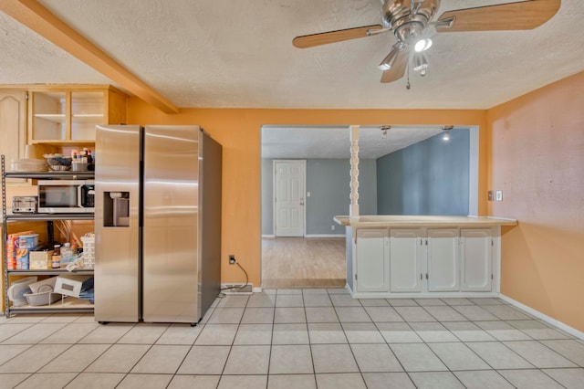 kitchen featuring a textured ceiling, stainless steel appliances, and light tile patterned floors