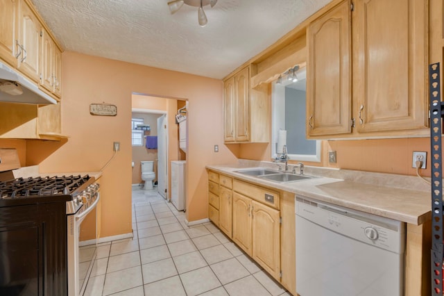 kitchen featuring light tile patterned floors, a textured ceiling, light brown cabinetry, sink, and white appliances