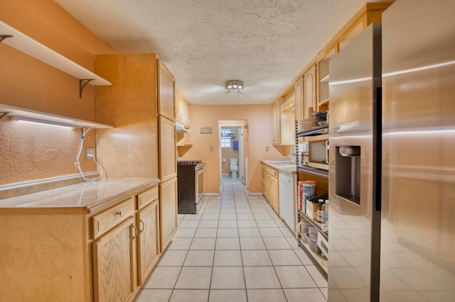 kitchen with appliances with stainless steel finishes, sink, a textured ceiling, light tile patterned floors, and light brown cabinets