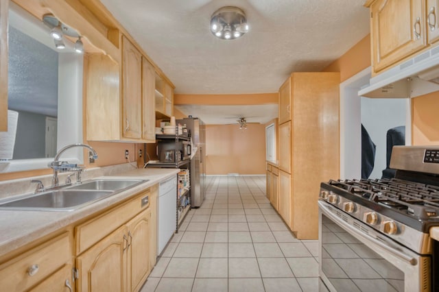 kitchen featuring light brown cabinets, stainless steel gas range oven, sink, and ceiling fan