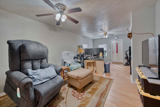 living room featuring ceiling fan, a textured ceiling, and light hardwood / wood-style flooring