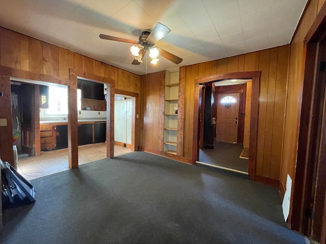 unfurnished living room featuring wooden walls and ceiling fan