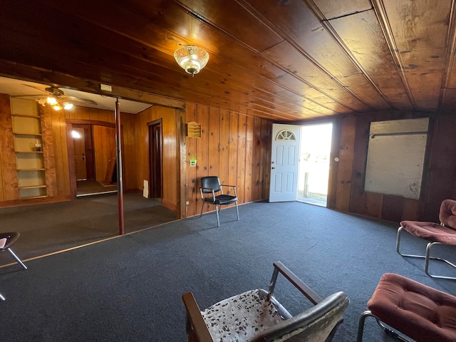 interior space featuring wooden walls, wood ceiling, carpet flooring, and ceiling fan