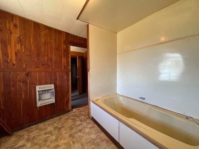 bathroom featuring heating unit, a tub, and wood walls