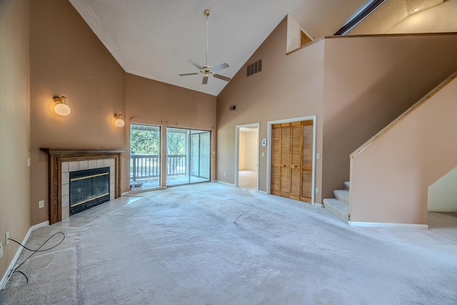 unfurnished living room featuring light carpet, high vaulted ceiling, a tile fireplace, and ceiling fan