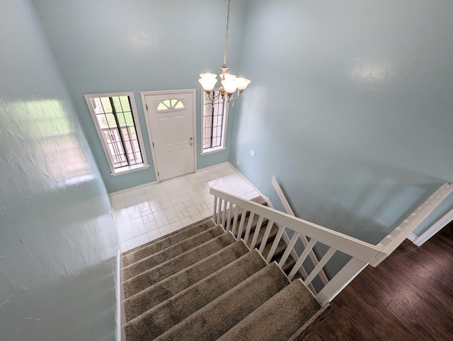 staircase featuring hardwood / wood-style flooring, lofted ceiling, and an inviting chandelier