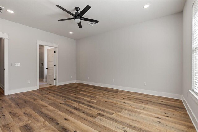 empty room with a wealth of natural light, hardwood / wood-style flooring, and ceiling fan