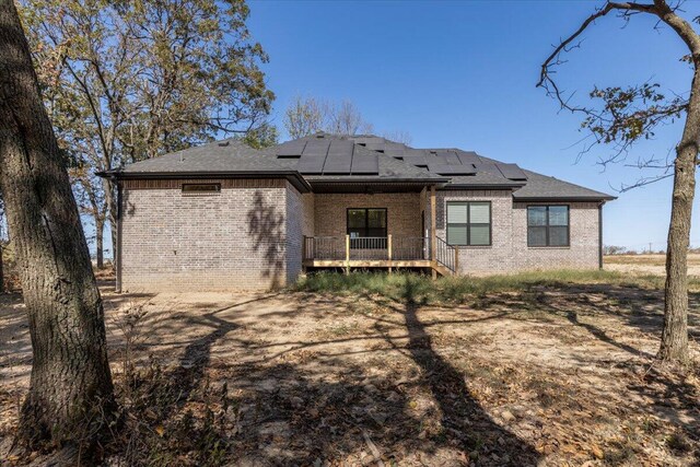 rear view of property featuring a porch and solar panels