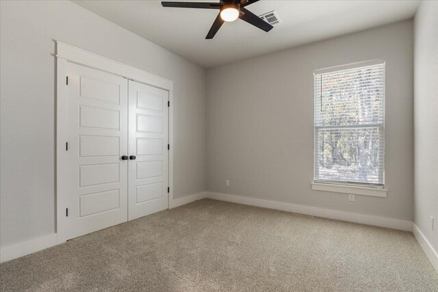 unfurnished bedroom with carpet, a closet, and ceiling fan