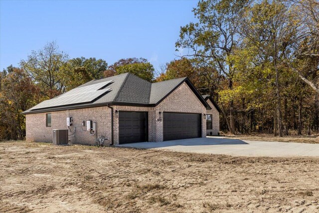 view of side of property featuring a garage, cooling unit, and solar panels