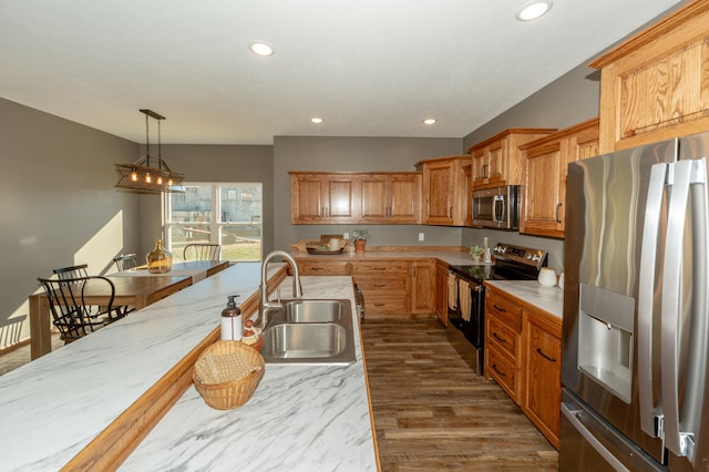 kitchen featuring stainless steel appliances, dark wood-type flooring, sink, a notable chandelier, and decorative light fixtures