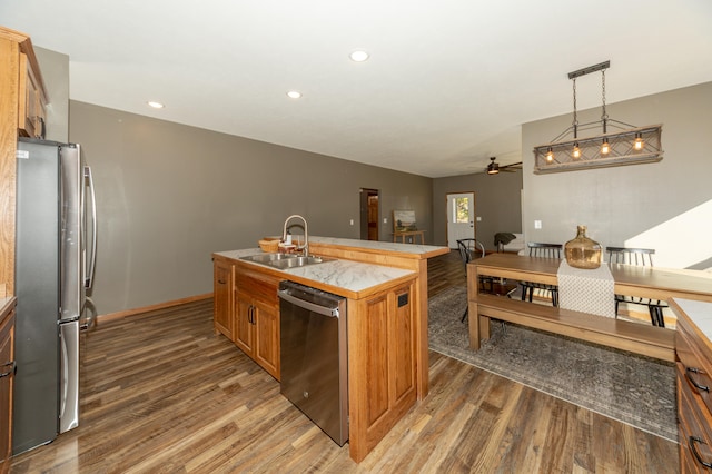 kitchen with dark hardwood / wood-style floors, an island with sink, stainless steel appliances, sink, and decorative light fixtures