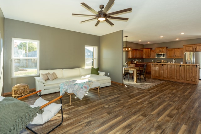 living room with dark hardwood / wood-style floors, ceiling fan with notable chandelier, and plenty of natural light