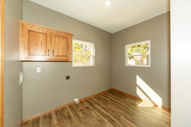 laundry room with wood-type flooring, hookup for an electric dryer, and cabinets