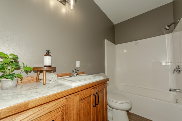 full bathroom featuring  shower combination, vanity, vaulted ceiling, and toilet